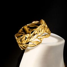 a close up of a gold ring on a white display stand in front of a black background