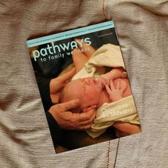 the book pathways to family wellness is laying on a bed next to an adult's hand holding a baby