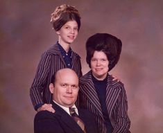 an older man and two younger women posing for a family photo in front of a brown background