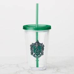 a harry potter tumbler with a green straw and sly crest on the side, sitting on a marble surface