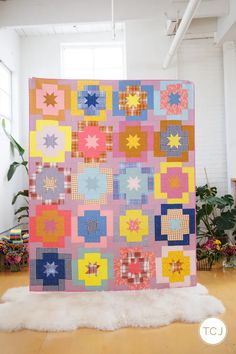 a large colorful quilt is on display in the middle of a room with white fur