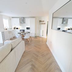 a living room filled with furniture next to a kitchen and dining room table on top of a hard wood floor