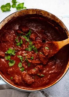 a pot filled with meat and garnish on top of a table