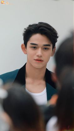 the young man is looking at his reflection in the mirror while wearing a white t - shirt and black blazer