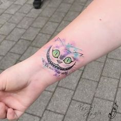 a person with a cat tattoo on their left wrist and hand holding the other arm