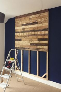 a ladder is sitting in front of a wooden paneled wall with blue paint on it