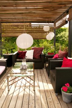 an outdoor living area with couches, tables and lamps hanging from the rafters