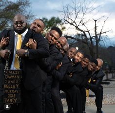 a group of men in suits and ties posing for the camera with their arms around each other