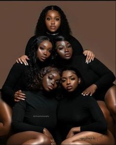 four women in black bodysuits sitting on top of each other with their arms around one another