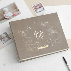 a baby's photo album with pictures and writing on it next to a pen