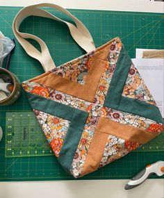 a quilted bag sitting on top of a cutting board next to scissors and tape