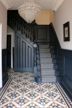 a chandelier hanging from the ceiling in front of a stair case and tiled floor