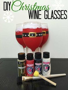 two wine glasses with santa clause on them sitting next to other bottles and supplies for making christmas wine