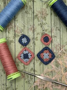 two spools of thread are next to some crocheted earrings