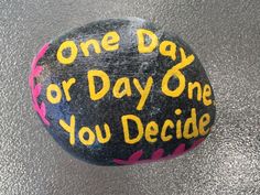 a painted rock that says one day or day one you decide