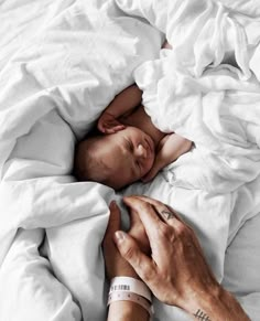 a man holding a baby in his arms while laying on top of a white blanket