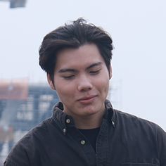 a man looking at his cell phone while standing in front of a cityscape