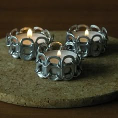 three lit candles sitting on top of a stone coaster with metal rings around the edges