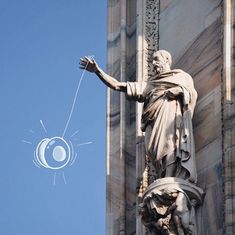 an image of a statue on the side of a building that has a string attached to it