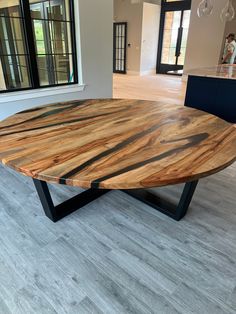 a large wooden table sitting in the middle of a living room next to a window