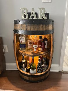 a wooden barrel filled with liquor bottles on top of a hard wood floor