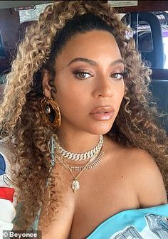 a woman with curly hair sitting in a car looking off to the side and wearing jewelry on her neck