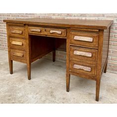 an old wooden desk with drawers on the bottom and one drawer at the top, in front of a brick wall