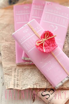 two pink candy bars wrapped in twine and tied with a bow, sitting on top of a piece of newspaper