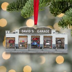 a christmas ornament hanging from the side of a tree with cars parked in front of it