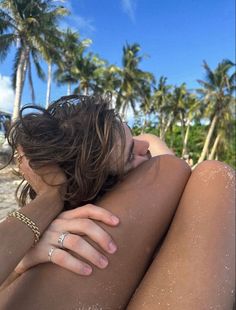 a woman laying on top of a sandy beach next to palm trees