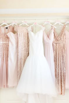 bridesmaids in pink and gold gowns hanging on the wall with their dresses