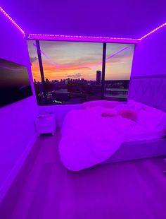 a bed in a room with purple lights on the walls and a large window that overlooks a cityscape