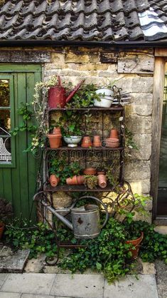 an old garden shed with potted plants and pots on the outside wall stock photo - image