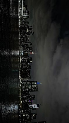 an aerial view of the city skyline at night with dark clouds in the sky and buildings lit up