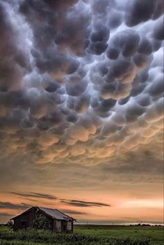 the sky is filled with clouds over an old barn