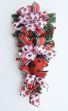 a red and white bow with ladybug on the front is attached to a wall