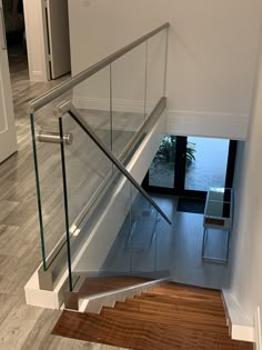 a staircase with glass railing and wooden flooring