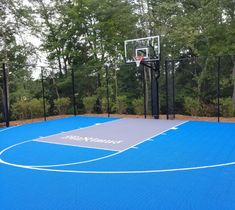 an outdoor basketball court surrounded by trees and fenced in area with blue tarp