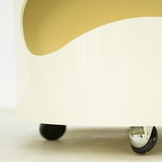 a close up of a white and yellow table with wheels on the bottom, against a white background