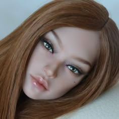 a close up of a doll with long red hair