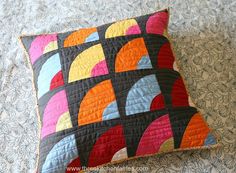 a colorful quilted pillow sitting on top of a bed