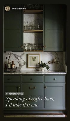 a kitchen with gray cabinets and marble counter tops, gold pulls on the cupboards