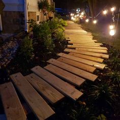 some lights that are on the side of a wooden walkway in front of a house