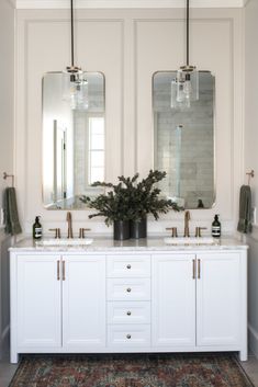 a bathroom with two sinks and mirrors on the wall next to a rug in front of it