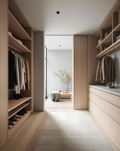 an empty walk in closet with wooden shelves and clothes on hangers next to it