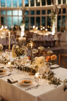 the table is set with flowers and candles for an elegant wedding reception at night time