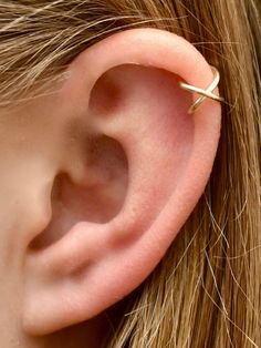 a close up of a person's ear with a small gold ring on it