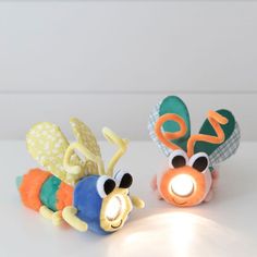 two small stuffed animals sitting next to each other on a table with a light in front of them