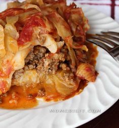 a white plate topped with lasagna covered in meat and cheese next to a fork