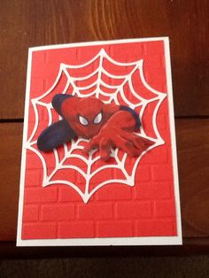 a spider - man card on a table with a red brick wall in the background